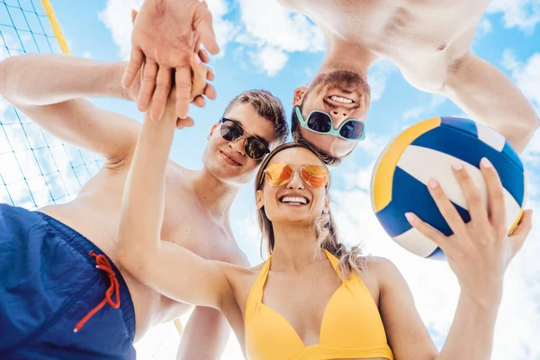 Vrienden met beachvolleybal neerkijkend op de camera — Stockfoto