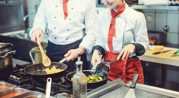 Szakácsok csapata a konyhában fantasztikus ételeket készít serpenyőben. — Stock Fotó