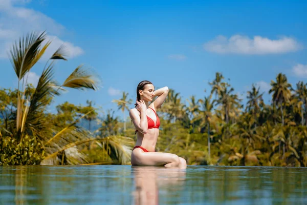 Nő a trópusi nyaralás ül a víz a medence — Stock Fotó
