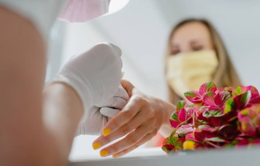 Tırnak sanatları stüdyosundaki müşteri koruyucu yüz maskesi takıyor.