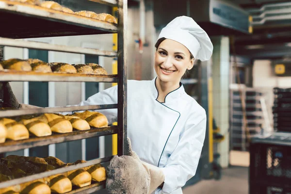 Wanita Baker mendorong lembaran dengan roti dalam oven memanggang — Stok Foto