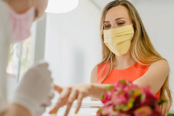 Cliente no estúdio de arte de unhas usando uma máscara protetora — Fotografia de Stock