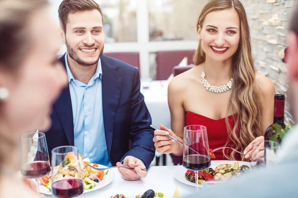 Две веселые пары болтают в хорошем ресторане — стоковое фото