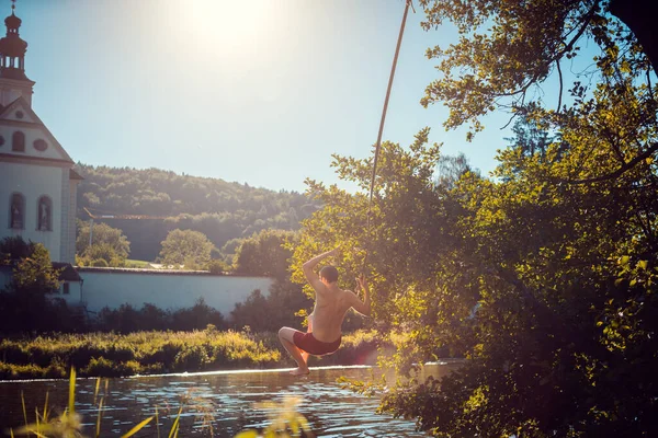 El hombre balanceándose sobre una cuerda en el agua de un río — Foto de Stock