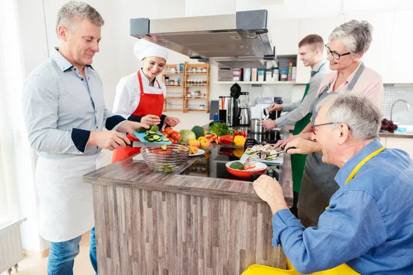 Chef mostrando aos estagiários os segredos da culinária saudável em sua cozinha — Fotografia de Stock