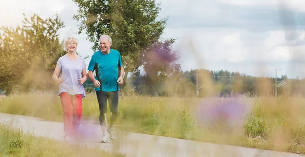 Ajuste y pareja mayor activa corriendo al aire libre como ejercicio — Foto de Stock