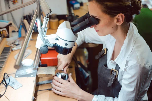 Fleißige Juwelierin arbeitet an ihrer Werkbank am Mikroskop — Stockfoto