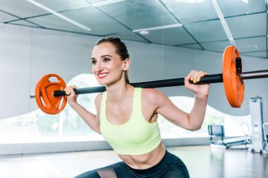 İşlevsel eğitim sırasında boynunun arkasında halter tutan kararlı bir kadın.