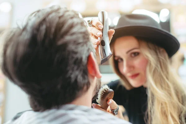 Kobieta fryzjer cięcie i przycinanie brody klienta w jej sklepie — Zdjęcie stockowe