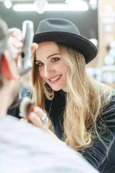 Woman barber cutting and trimming beard of client in her shop