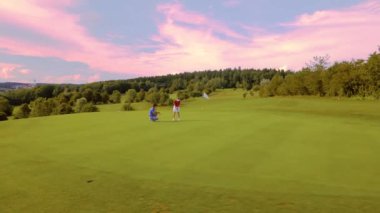 Kadın ve golf profesyonelinin yörüngesinde golf oynuyorlar.