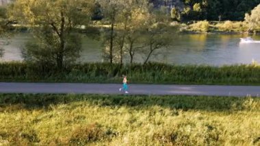 Kadın hava aracıyla yolda koşuyor, manzarayı gösteriyor.