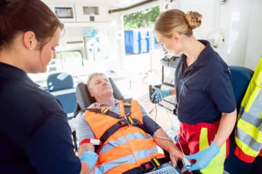 Acil servis doktoru ambulansta yaralı adamla konuşuyor.