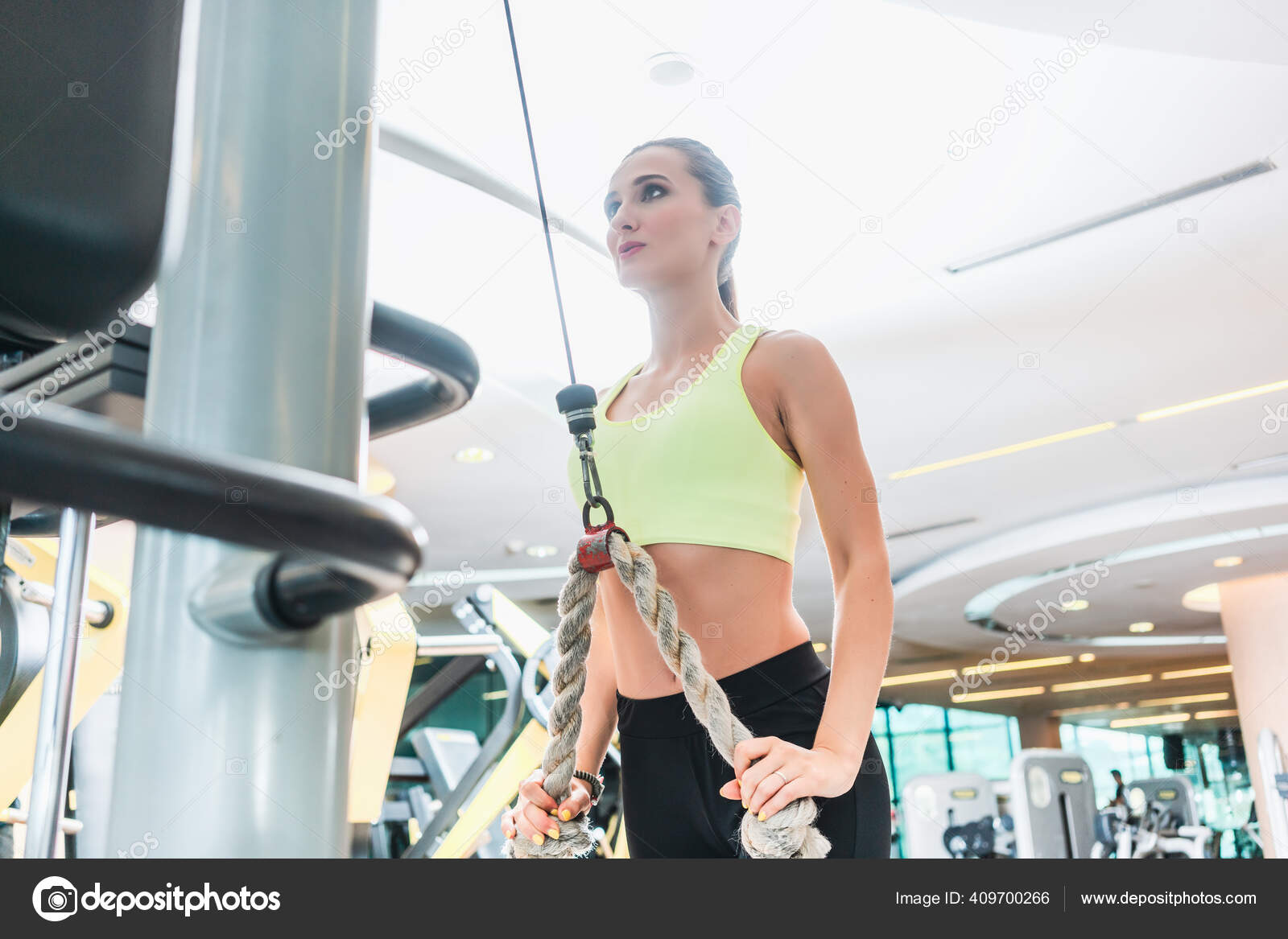 Visão de baixo ângulo de uma bela mulher apta a exercer extensão de tríceps  de corda de cabo — Foto © Kzenon #409700266, image size:1600x1167