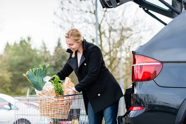 Wanita memuat bahan makanan setelah berbelanja ke bagasi mobilnya — Stok Foto