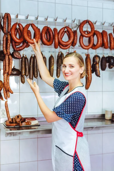 Femme recommandant activement des saucisses dans sa boucherie — Photo