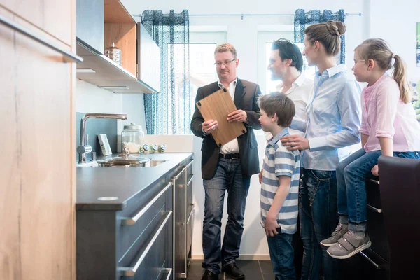 Salesman showing family the features of a new kitchen — Stock Photo, Image