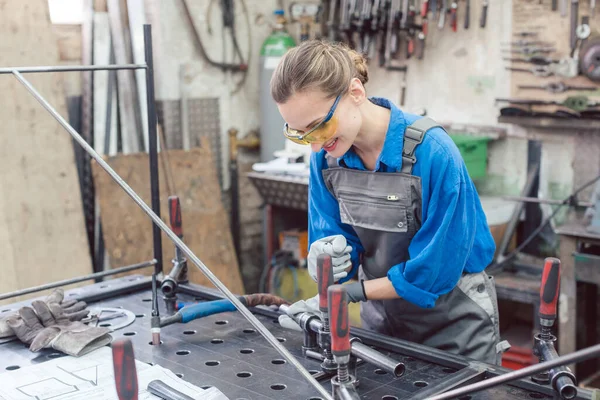 Mulher em oficina de metal com ferramentas e peça de trabalho — Fotografia de Stock