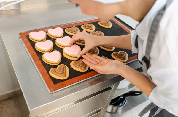Suikerbakkersvrouw die banketbakkerszak gebruikt om room bovenop koekjes te doen — Stockfoto