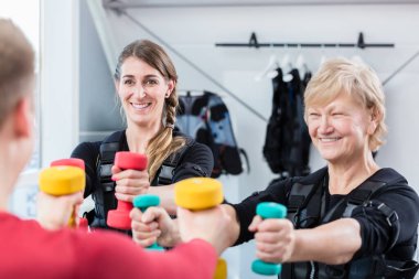 Kablosuz EM spor salonunda dambılları olan yaşlı ve genç bir kadın.