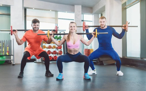 Spor salonunda ağırlık egzersizi yapan bir grup fit genç. — Stok fotoğraf