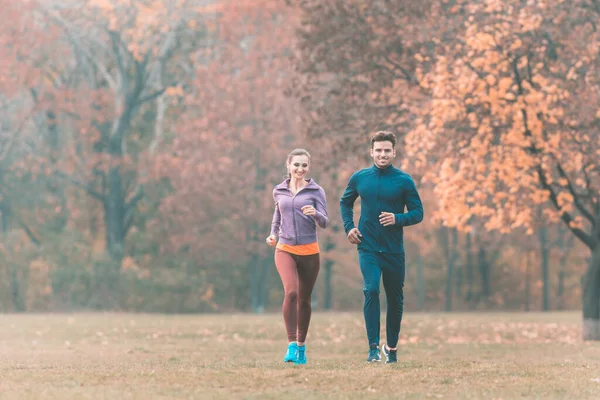Couple in wonderful fall landscape running for better fitness — Stock Photo, Image