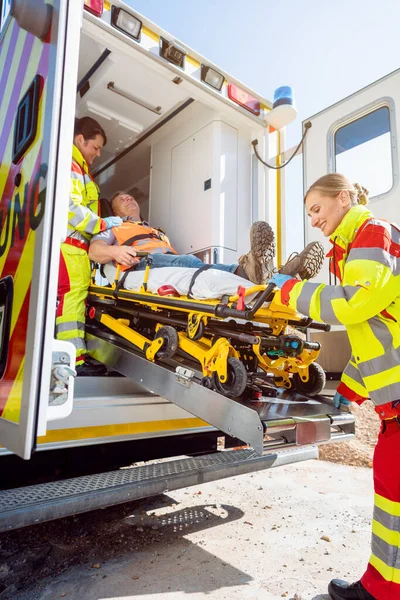 Sağlık görevlileri yaralı adamı ambulansla sedyeye koyuyor. — Stok fotoğraf