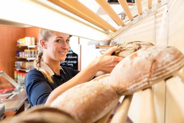 Panificio donna mettendo il pane nello scaffale negozio — Foto Stock