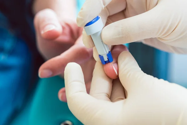 Infermiera foratura dito del paziente per spremere il campione di sangue per il test — Foto Stock
