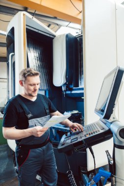 Endüstriyel atölye işçisi bir cnc makinesini programlıyor