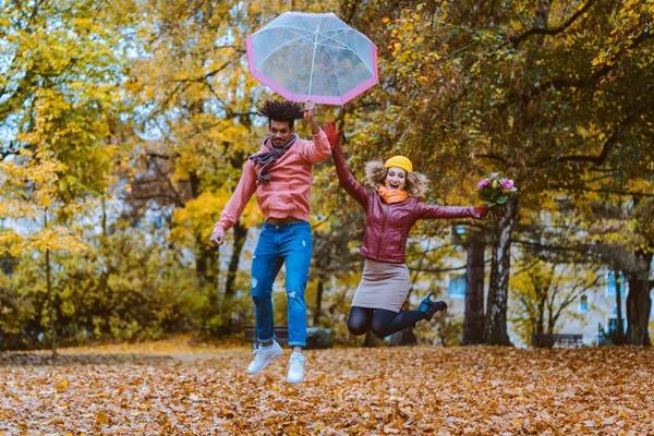 Hombre y mujer saltando alegremente en el parque de otoño — Foto de Stock