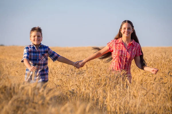 Girl and boy running on field with ripe wheat — Stock Photo, Image