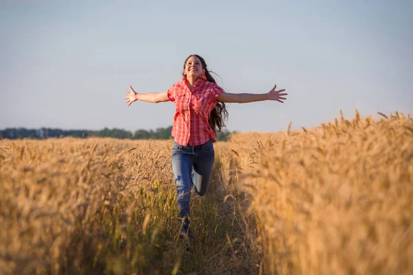 Giovane ragazza che corre sul campo con grano maturo — Foto Stock