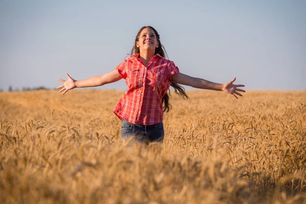 Giovane ragazza che corre sul campo con grano maturo — Foto Stock
