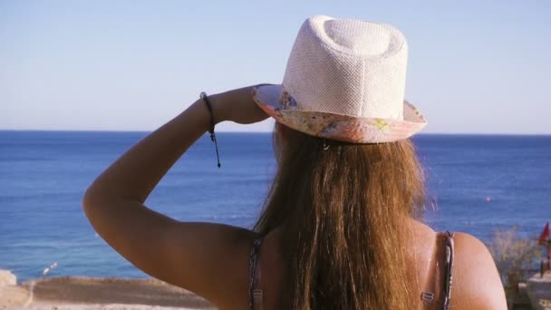 Chica en la costa mirando alrededor de mar azul — Vídeo de stock