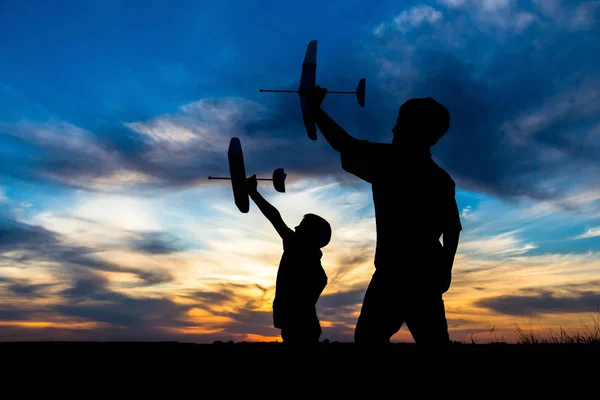 Silhouette de deux garçons avec ses avions contre le coucher du soleil — Photo