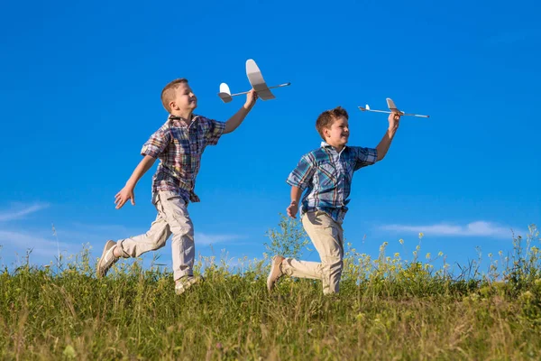 Двое детей бегают с его самолетами на зеленом поле — стоковое фото