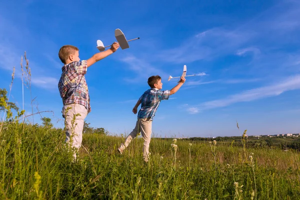 Two kids launch his airplans at field — Stock Photo, Image