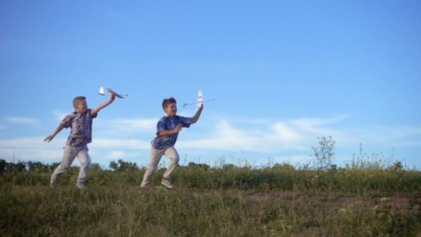 Twee jongens lopen met zijn vliegtuigen op het veld — Stockvideo