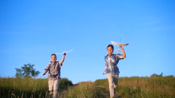 Zwei Jungen laufen mit seinen Flugzeugen auf das Feld — Stockvideo