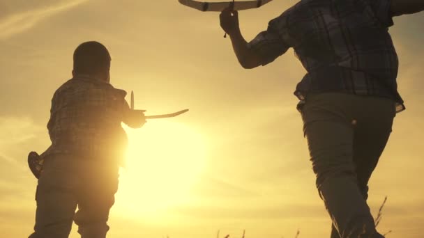 Силуэт двух мальчиков, бегающих с самолетами на закате — стоковое видео