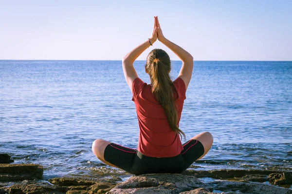 Молодая девушка медитирует на побережье в позе йоги — стоковое фото