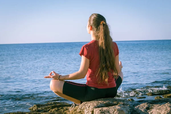 Ung flicka mediterar på kusten i yogaställning — Stockfoto