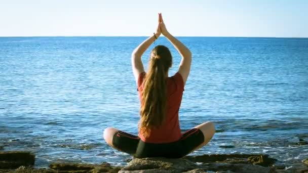 Junges Mädchen meditiert an der Küste in Yoga-Pose — Stockvideo