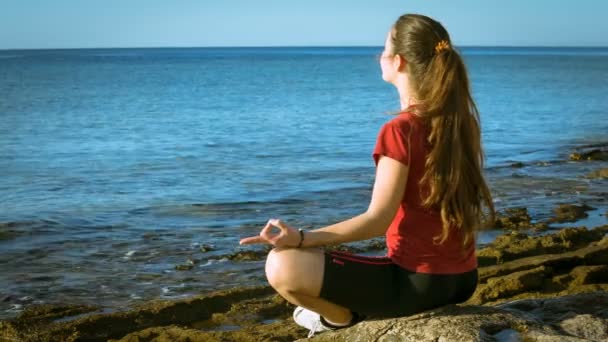 Jeune fille méditant sur la côte en pose de yoga — Video