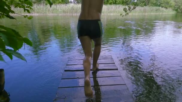 Pojken hoppar till floden från piren — Stockvideo