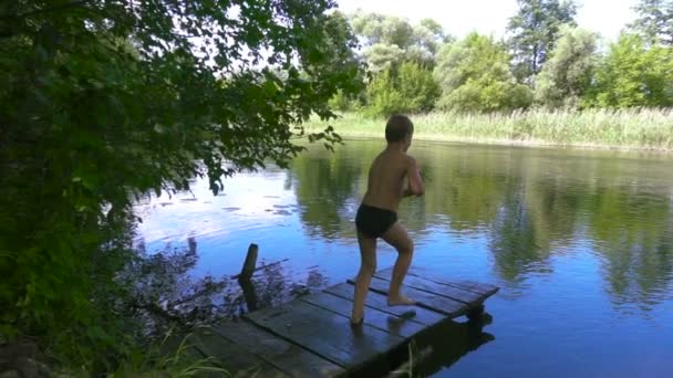 Jongen springen naar de rivier vanaf pier — Stockvideo