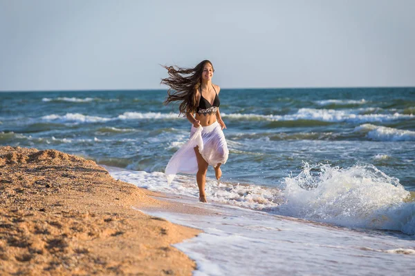 美丽的年轻女孩穿着白色的礼服运行在早晨冲浪 — 图库照片