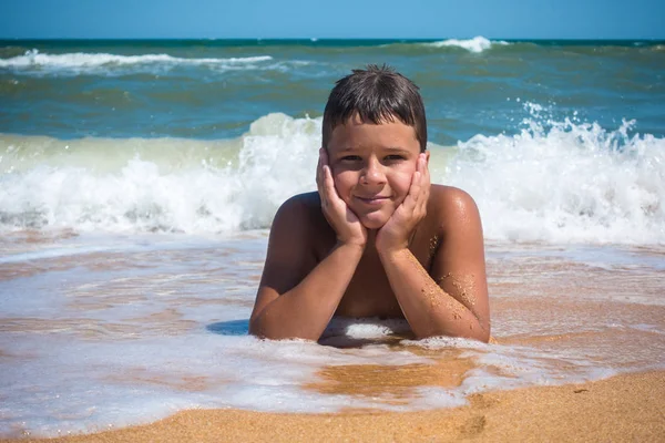 Uśmiechnięty chłopiec leżał na plaży, na zewnątrz — Zdjęcie stockowe