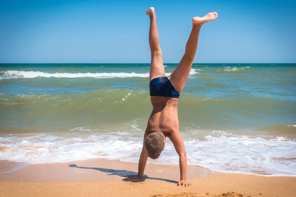 Ragazzo in piedi a testa in giù sulla spiaggia — Foto Stock